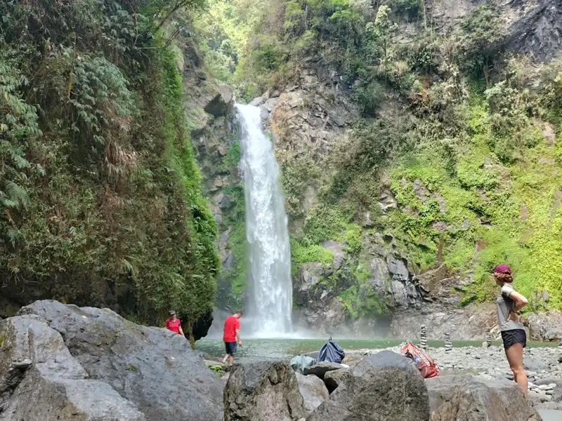 Wanderer pausieren am Fuße eines Wasserfalls.