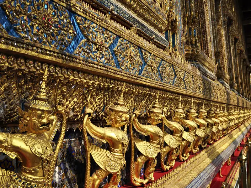 Goldene Garuda-Statuen an einer Tempelwand.