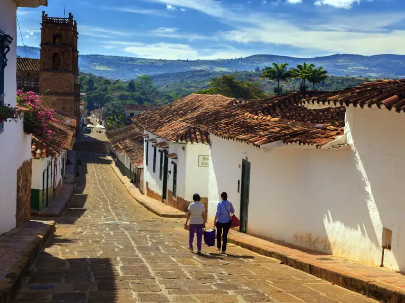 Gepflasterte Straße mit weiß getünchten Häusern und Kirchturm im Hintergrund