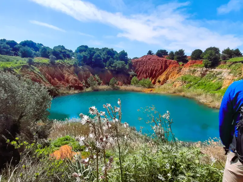Türkisfarbener See umgeben von roter, felsiger Landschaft.