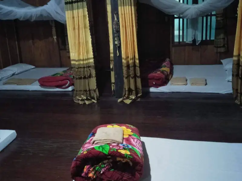 Schlafbereich mit Betten, Decken, Kissen und Moskitonetzen.