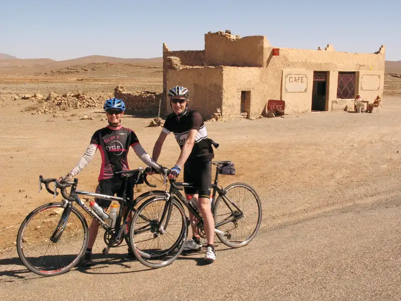 Zwei Radfahrer pausieren während ihrer Radtour in der Wüste vor einem Café.