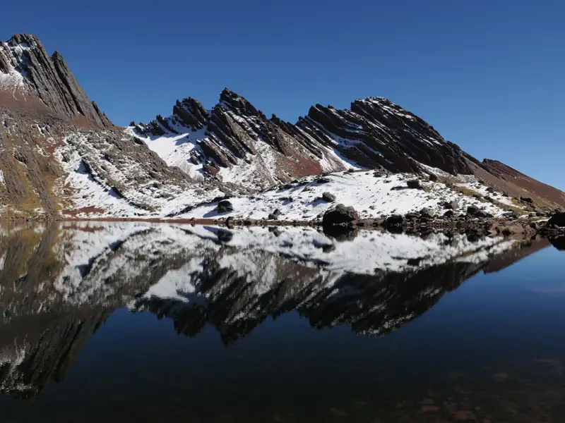 Stille Berglandschaft mit einem See, der die schneebedeckten Gipfel spiegelt.