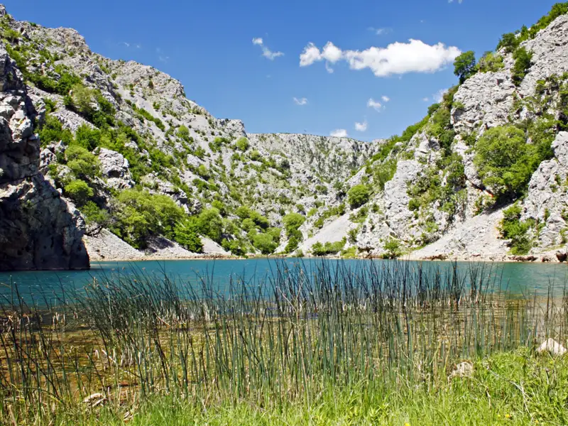 Blauer See inmitten einer felsigen Hügellandschaft.