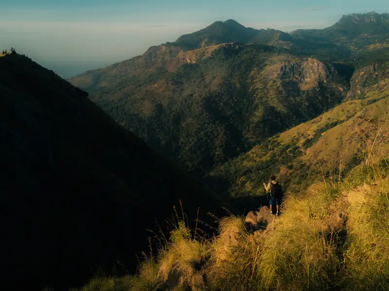 Wanderer betrachtet die Hügellandschaft.
