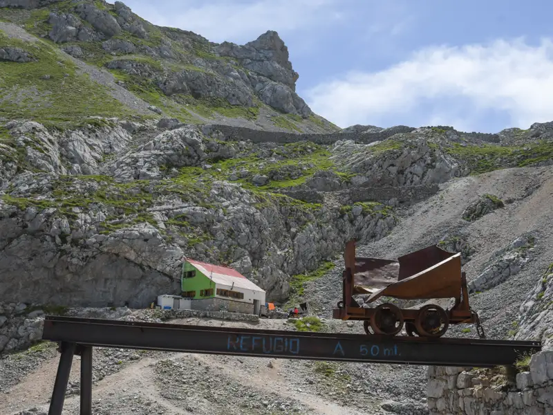 Berghütte in den Bergen mit einem alten Minenwagen, der auf die Nähe der Hütte hinweist.