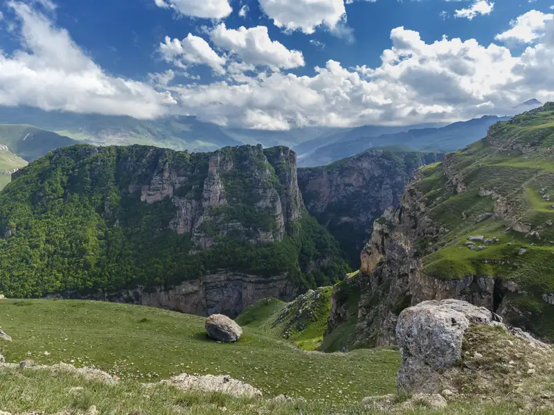 Panoramablick auf eine tiefe Schlucht mit bewachsenen Hängen und Felsformationen.