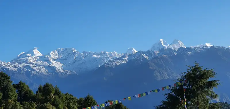 Schneebedeckte Bergkette mit Gebetsfahnen, möglicherweise aufgenommen während einer Trekkingtour im Himalaya.