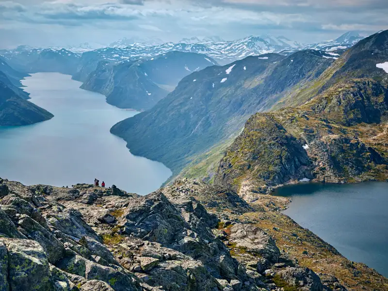 Panoramablick auf einen Fjord und schneebedeckte Berge von einem felsigen Aussichtspunkt.