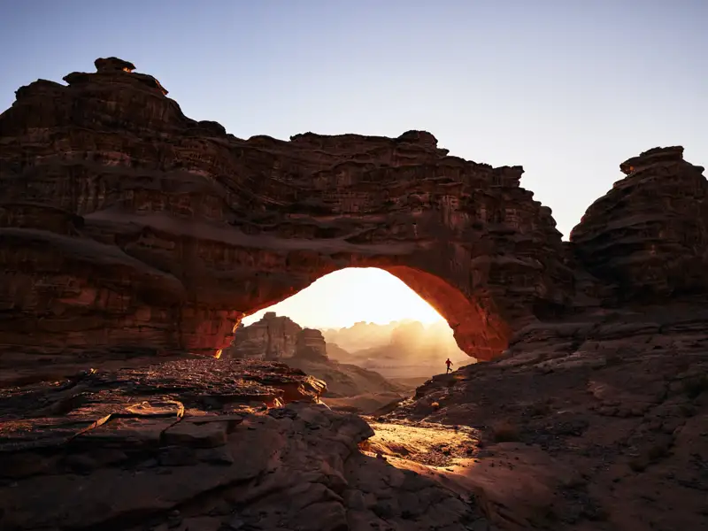 Sonnenaufgang durch einen natürlichen Felsbogen während der Reise.