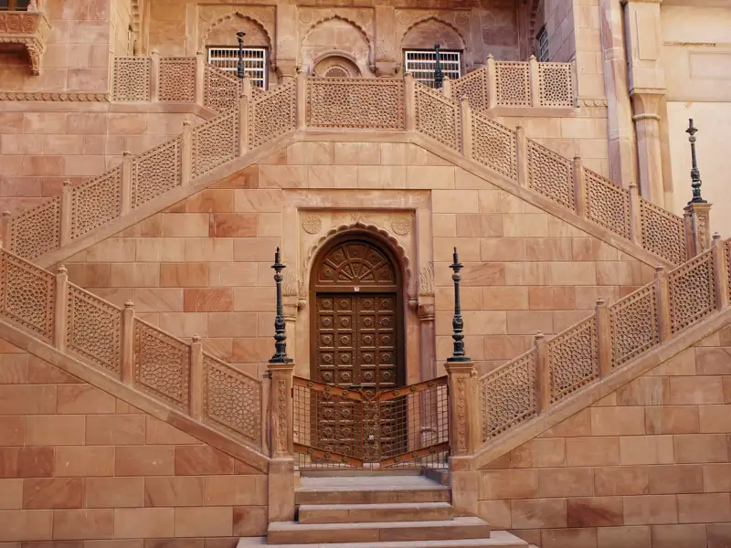 Sandsteintreppe mit kunstvollen Details und einer geschnitzten Holztür.