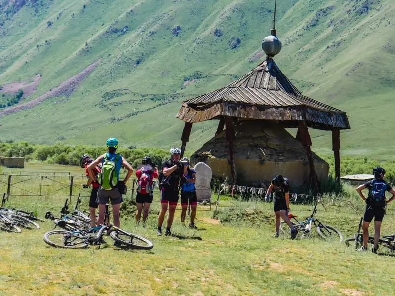 Radfahrergruppe pausiert während ihrer Tour an einem traditionellen Bauwerk in den Bergen.