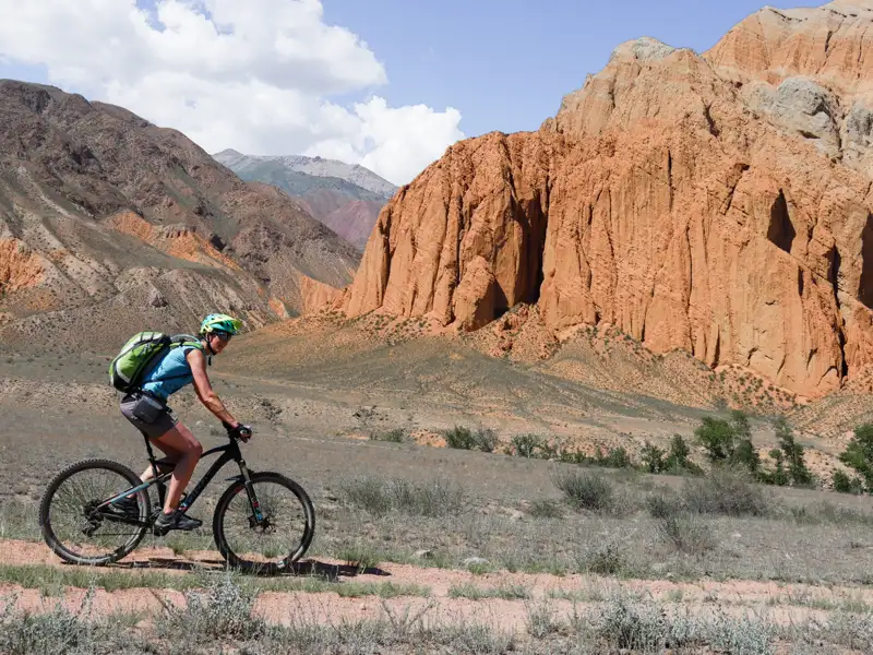 Mountainbiker fährt auf einem Weg vor einer Felsformation.