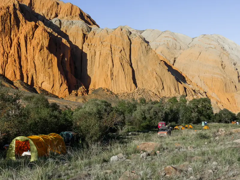 Campingplatz in einer bergigen Landschaft mit orangefarbenen Felsformationen.