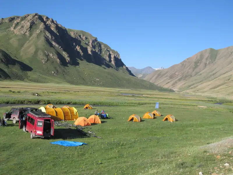 Reise-Basislager mit Zelten und Fahrzeugen im Tal.