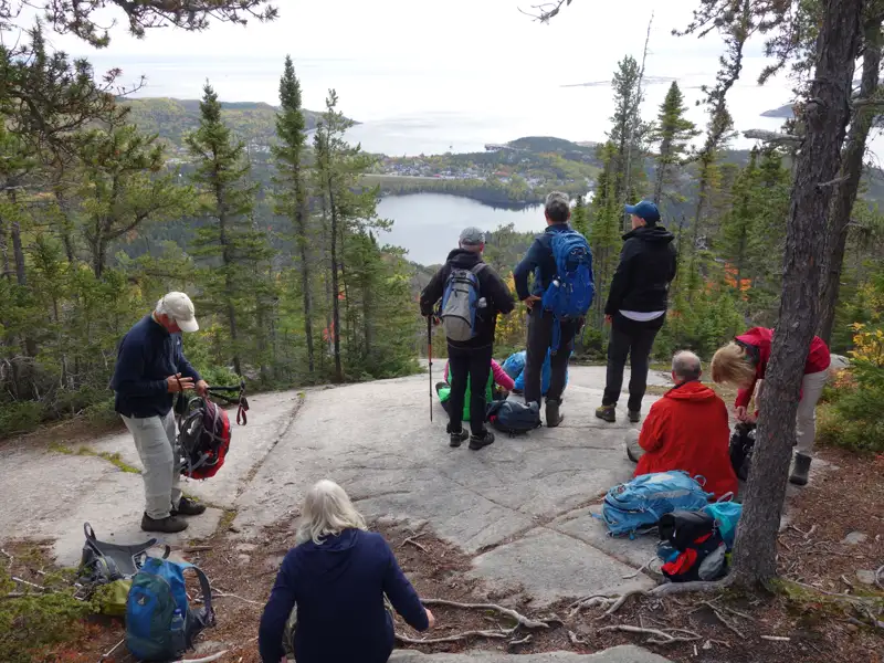 Wanderer ruhen sich auf einem felsigen Aussichtspunkt mit Blick auf die Küste aus.
