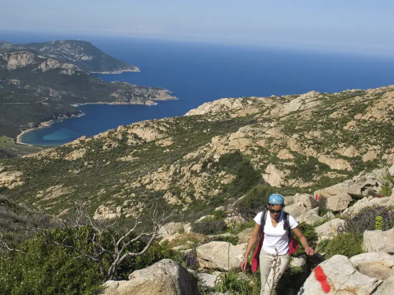 Wanderer auf einem markierten Küstenpfad mit Blick auf das Meer und die Buchten.