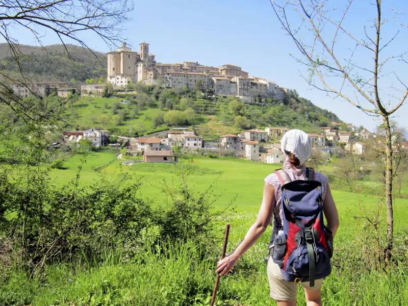 Wanderer mit Blick auf ein italienisches Bergdorf.
