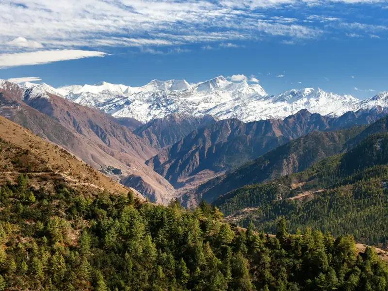 Schneebedeckte Bergkette und bewaldete Täler.