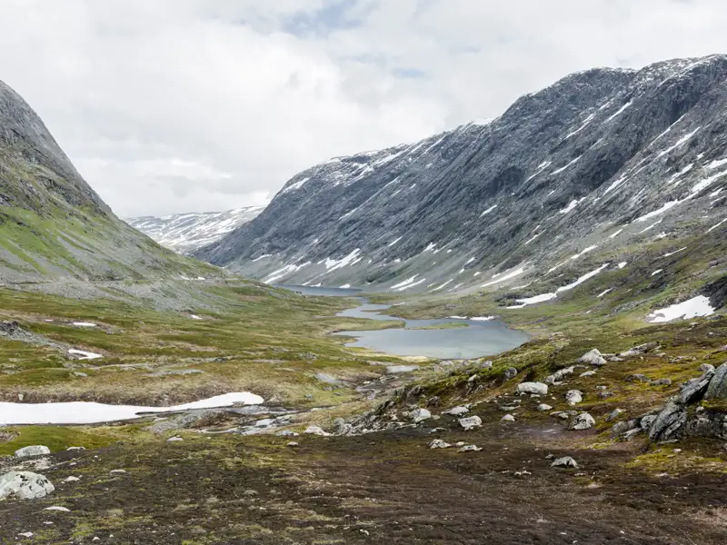 Alpenlandschaft mit See und Schneeresten.