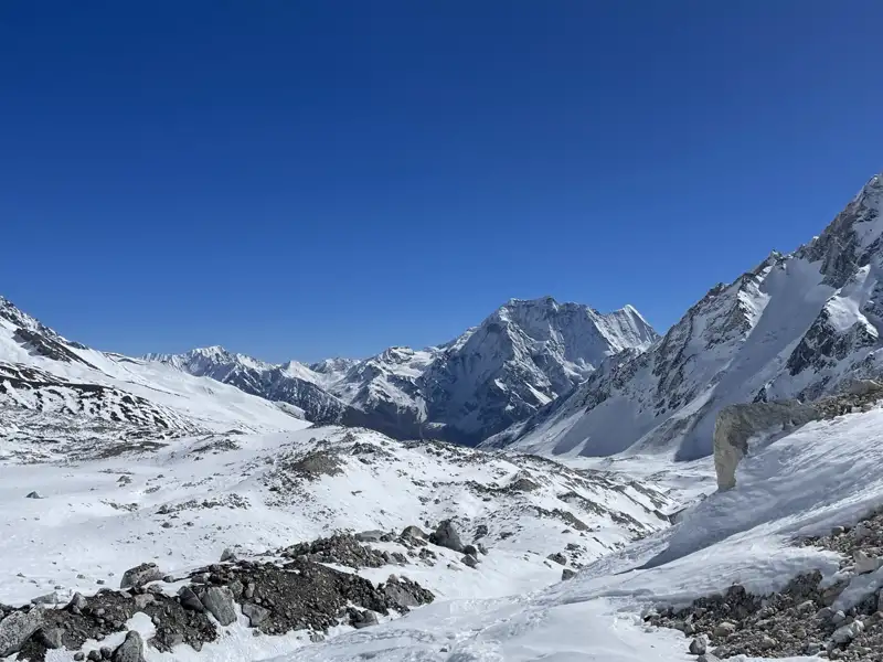 Panorama einer verschneiten Bergkette unter blauem Himmel.