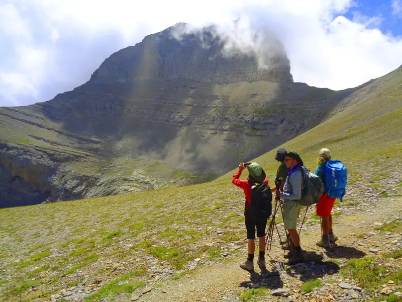 Wanderer mit Rucksäcken und Wanderstöcken betrachten und fotografieren einen Berg während ihrer Tour.