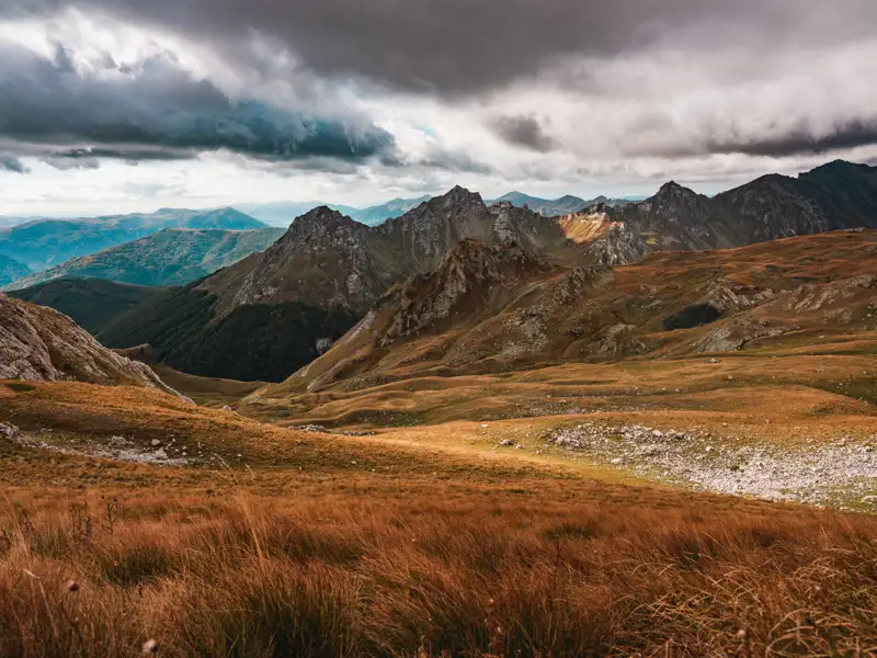 Herbstliche Berglandschaft unter dramatischem Himmel.