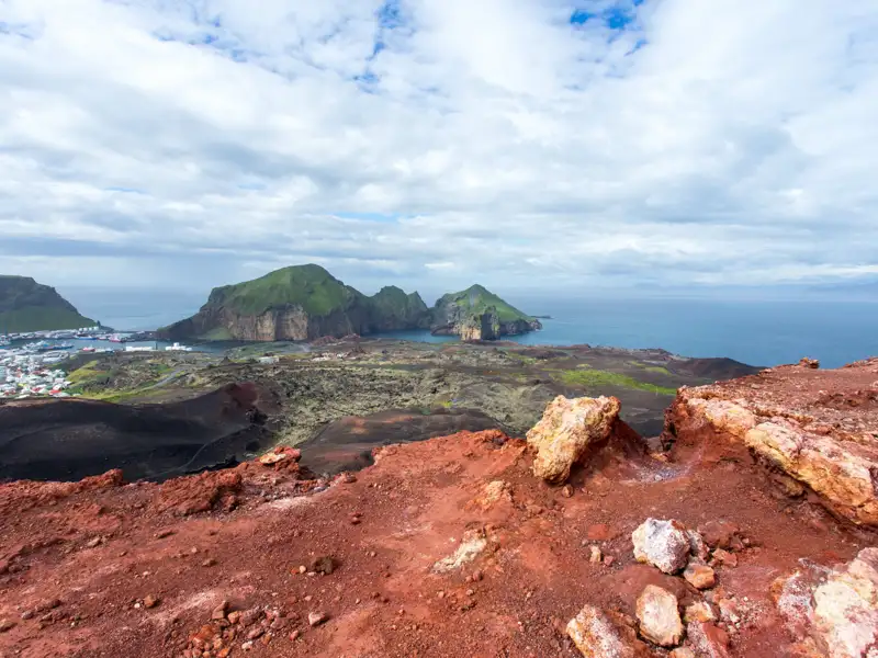 Panoramablick auf eine grüne Insel vom roten, felsigen Aussichtspunkt aus.