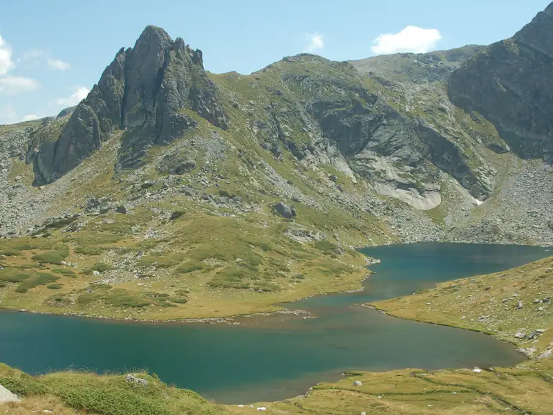 Zwei Bergseen in einer hochalpinen Landschaft mit felsigen Gipfeln und grünen Hängen.