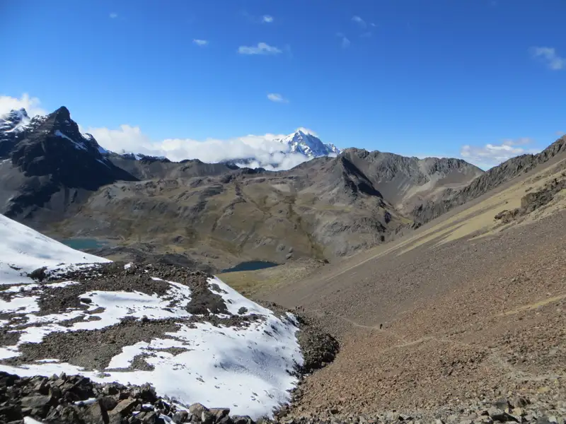 Hochgebirgspanorama mit Schnee, Seen und Bergpfad.