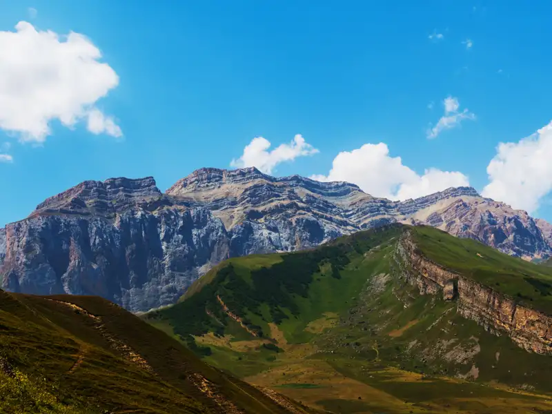 Spektakuläre Aussicht auf eine Bergkette mit felsigen Gipfeln und grünen Tälern.