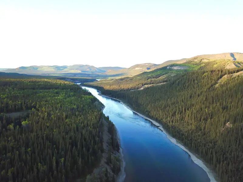 Luftaufnahme eines Flusses inmitten von Wäldern und Hügeln.
