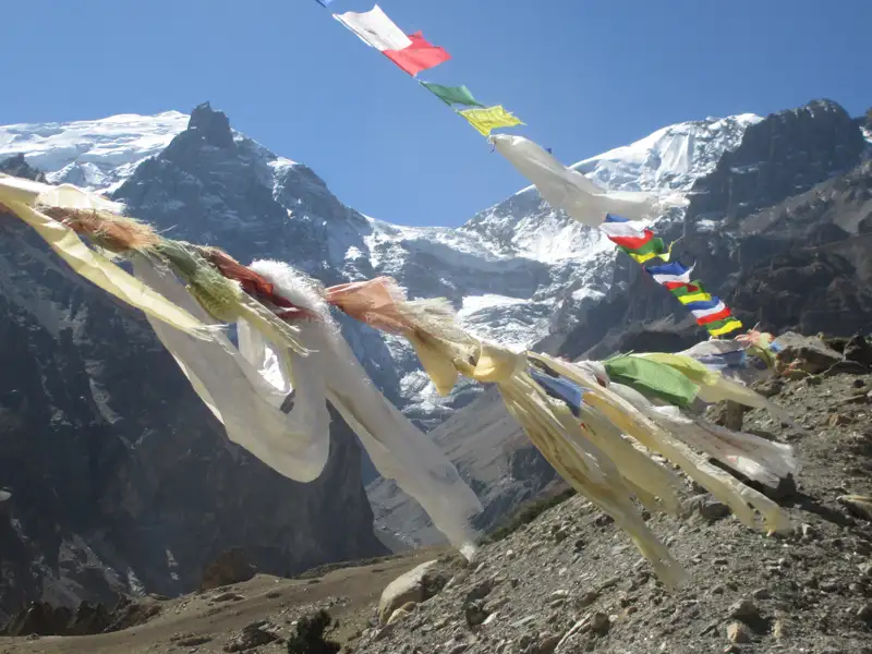 Gebetsfahnen im Wind mit Blick auf die schneebedeckten Gipfel des Himalayas.