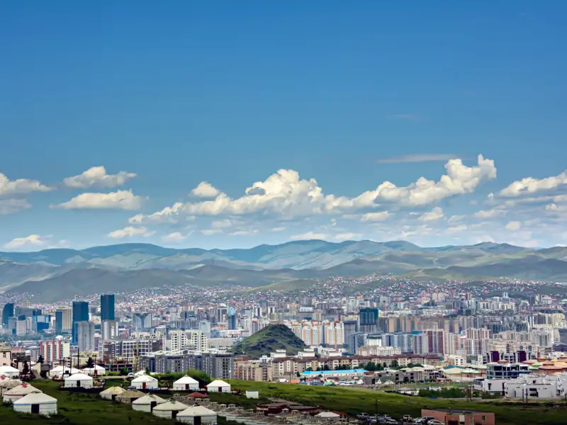 Stadtbild von Ulaanbaatar, Mongolei, mit Gebirge im Hintergrund und Jurtensiedlung im Vordergrund.