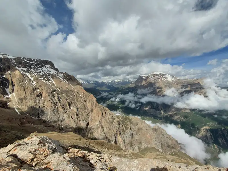 Panoramablick auf schneebedeckte Berggipfel und Wolkenformationen im Tal.