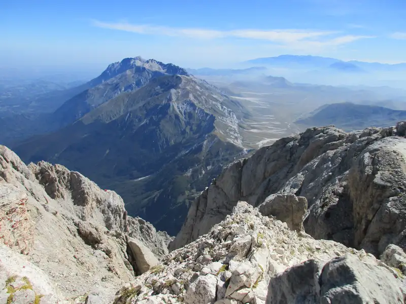 Aussicht von einem Berggipfel auf weitere Berge und ein Tal.