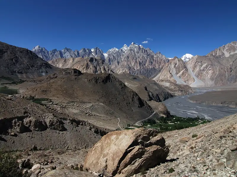 Panoramablick auf eine Bergkette mit einem Fluss im Tal und landwirtschaftlichen Flächen.