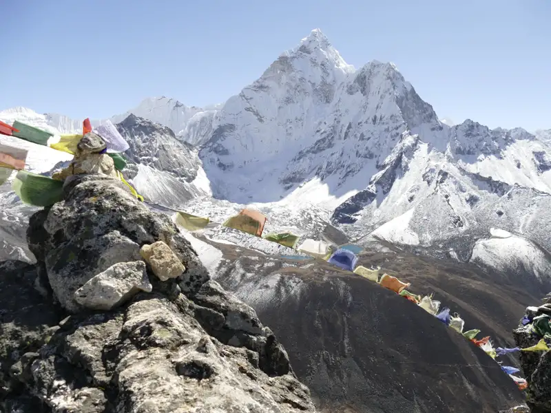 Gebetsfahnen und ein schneebedeckter Berggipfel im Himalaya.
