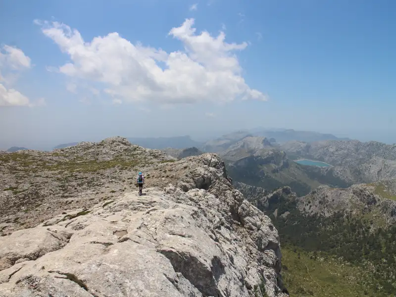 Wanderer auf einem Bergpfad mit Blick auf die umliegende Landschaft.