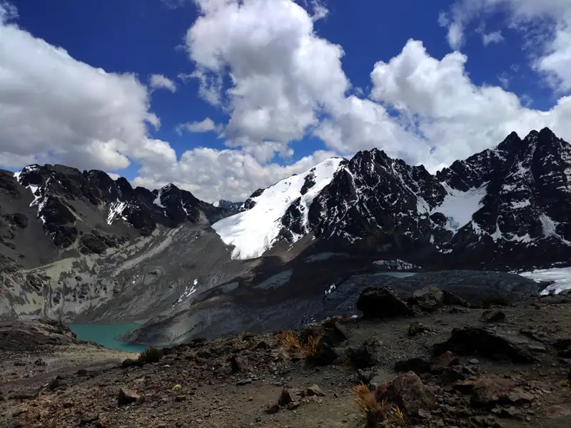 Spektakuläre Aussicht auf die schneebedeckten Gipfel und den Gletscher. Ein türkisfarbener See liegt eingebettet in der felsigen Landschaft.