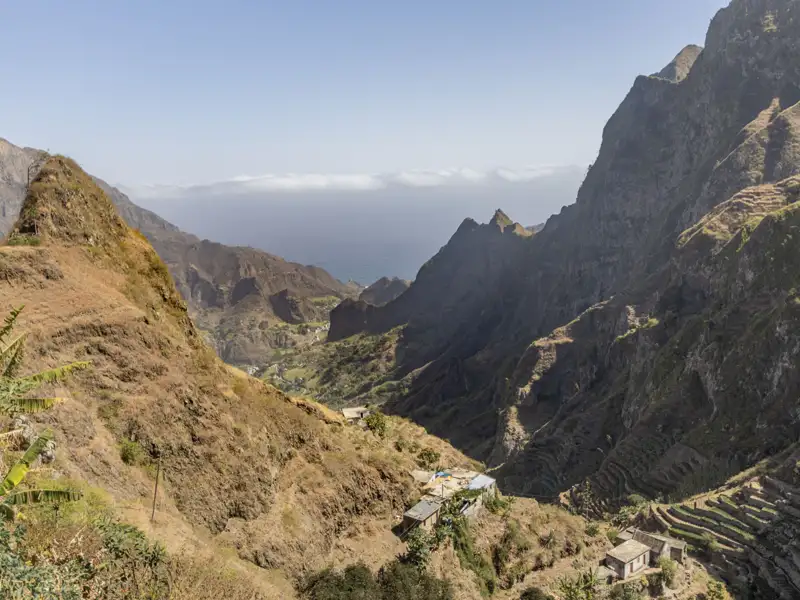 Aussicht auf ein Bergtal mit terrassierten Hängen und kleinen Häusern.