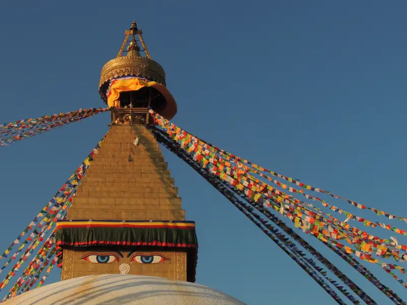 Nahaufnahme des Boudhanath Stupa mit seinen charakteristischen Augen und den umliegenden Gebetsfahnen.