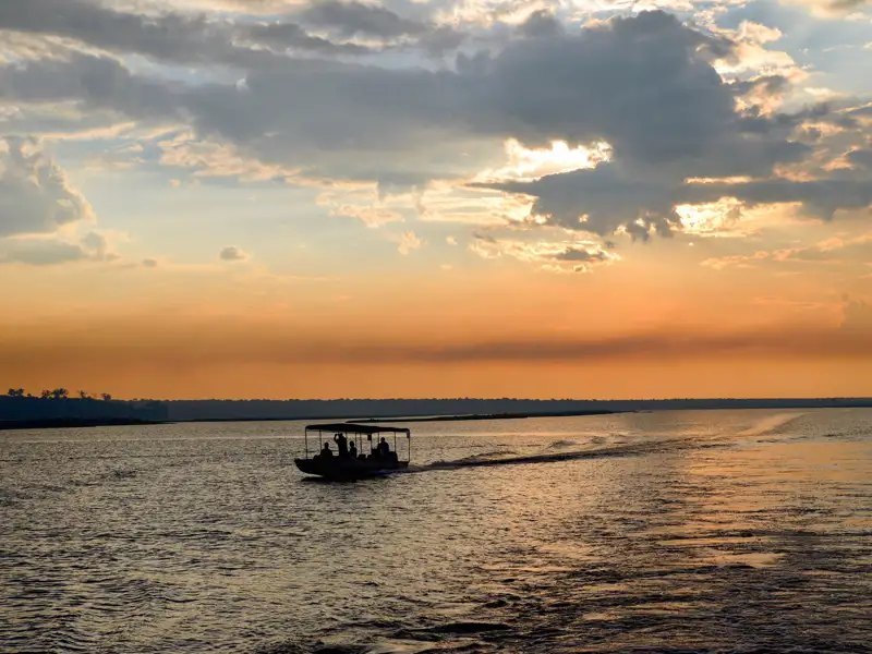 Boot mit Passagieren auf dem Fluss bei Sonnenuntergang.