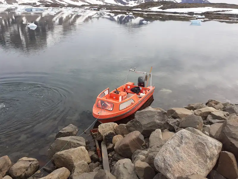 Orangefarbenes Boot am Ufer eines Bergsees, bereit für eine Erkundungstour.