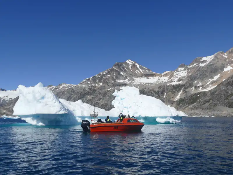 Bootstour in der Nähe eines Eisbergs mit Blick auf die Berge.