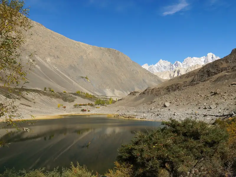 Panoramablick auf einen Bergsee mit schneebedeckten Gipfeln im Hintergrund.
