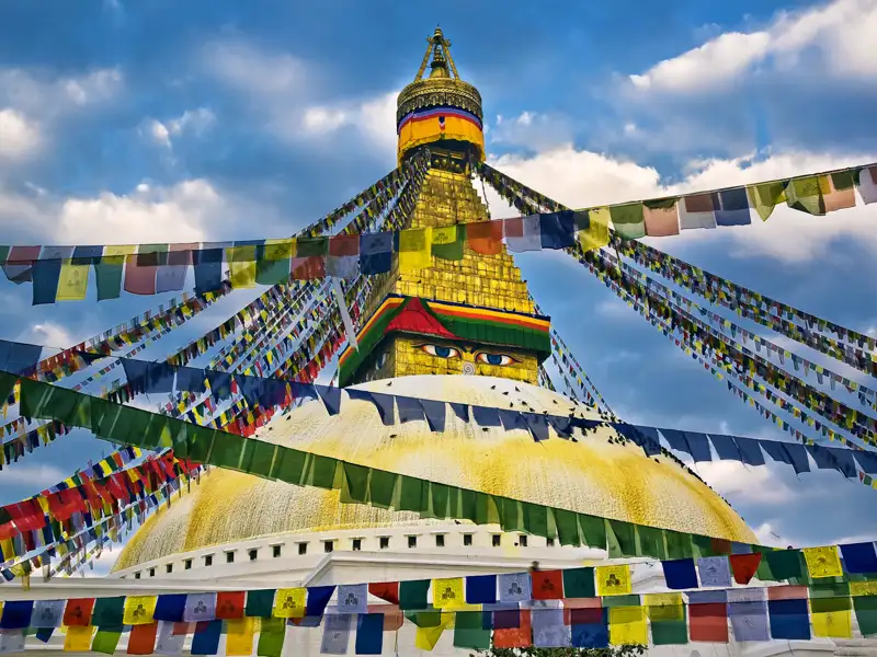 Der Boudhanath Stupa mit seinen charakteristischen Augen und den umgebenden Gebetsfahnen.