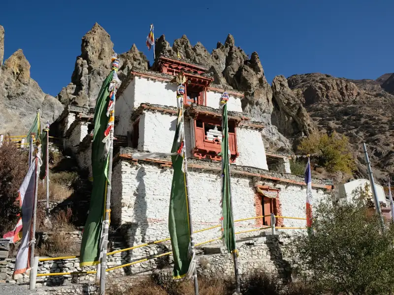 Weißes Gebäude mit Gebetsfahnen in den Bergen.