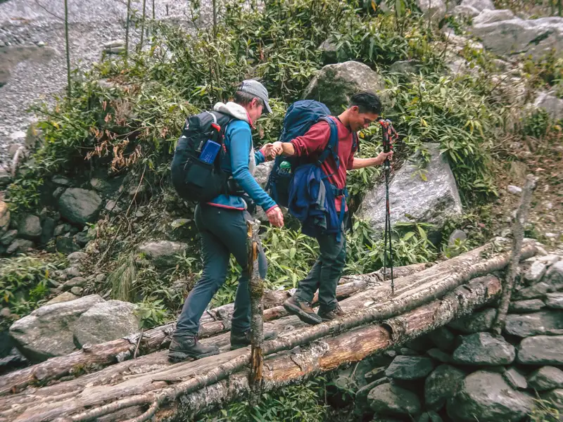 Wanderer überqueren eine Holzbrücke im Gebirge.