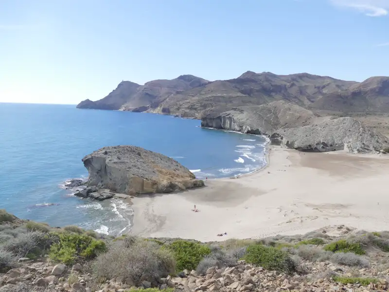 Abgelegene Bucht mit Sandstrand und Felsformationen im Hintergrund.